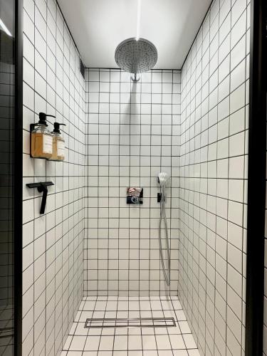 La salle de bains est pourvue d'une douche et de murs carrelés blancs. dans l'établissement Victoria Surf Studio d'Architecte, à Biarritz