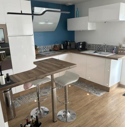 une cuisine avec des armoires blanches et une table en bois dans l'établissement Chambre dans une maison chaleureuse, à Fouquières-lès-Béthune