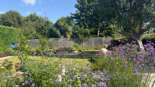 a garden with purple flowers and a bench at Bosham - private and self-contained double garden room in Chichester