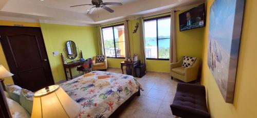 a bedroom with a bed and a chair and windows at Boca Chica Bay Eco Lodge in Boca Chica