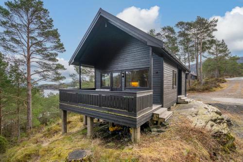 a black tiny house on a hill in the woods at Gunnarhytta, Valevåg in Valevåg