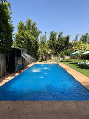 a large blue swimming pool with a water fountain at Villa luxueuse Marrakech Ourika in Ourika