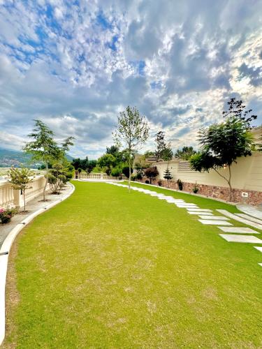a grassy yard with a fence and trees at Emerald Villa Swat in Ghurejo