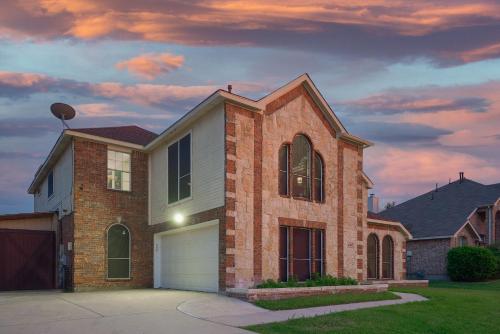 a brick house with a garage at dusk at Prestigious 5BR 3,5BA Holiday Home with Pool, Sauna, Game Room & Bar in Sachse