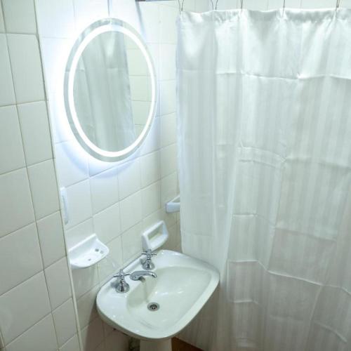 a white bathroom with a sink and a mirror at Ciervo de Oro in Villa Carlos Paz