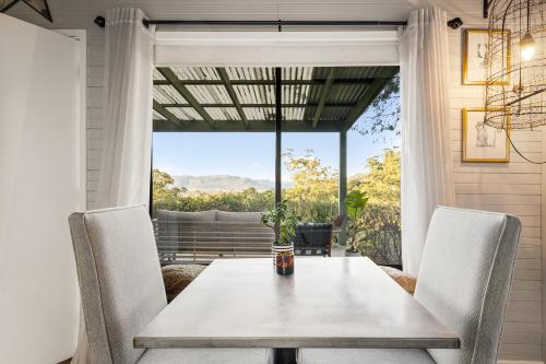 a dining room with a table and chairs and a window at Martha's Villa - panoramic, peaceful location in Kangaroo Valley