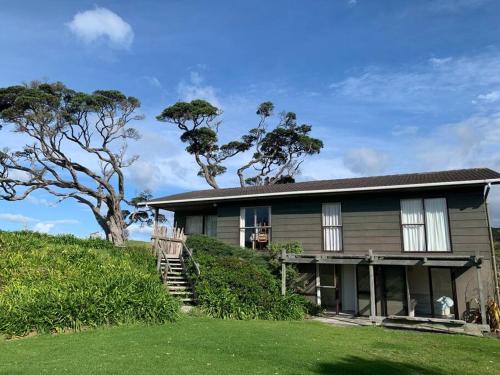 a house on a hill with a green yard at Elliot Bay - Hilltop Cottage in Rawhiti
