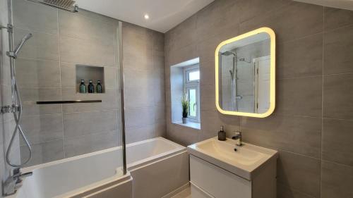 Un baño con ducha, lavabo y bañera. en Beautiful 4Bedroom 2Bath Wifi and Free Parking, en South Norwood