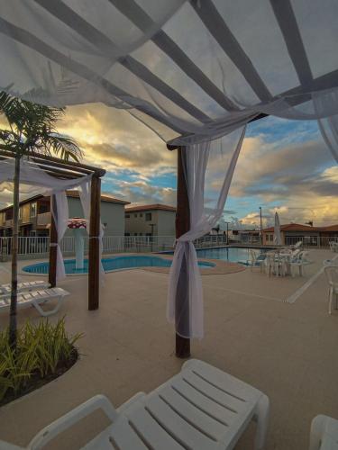 a patio with a white canopy and a pool at Ap 2 quartos tipo resort pé na areia 1 in Barra dos Coqueiros