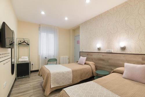 a hotel room with two beds and a tv at Hostal Art Madrid in Madrid