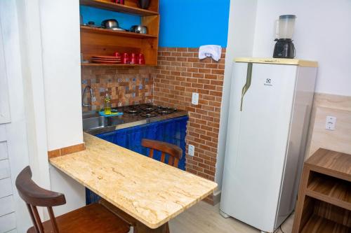 a kitchen with a wooden table and a refrigerator at Pousada Flat Castor in Natal