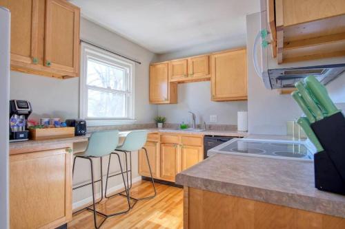 a kitchen with wooden cabinets and two bar stools at Close to Butler Uni, Cozy Home,Firepit,Free Parking in Indianapolis
