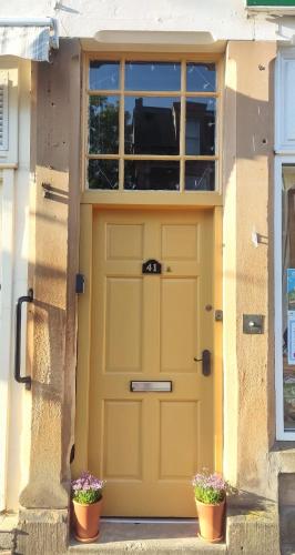 a yellow garage door with two potted plants at Acorn House Callander in Callander
