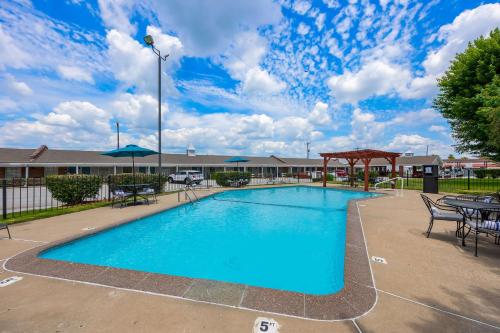a swimming pool with tables and chairs in front of a building at Best Western Coach House in Springfield