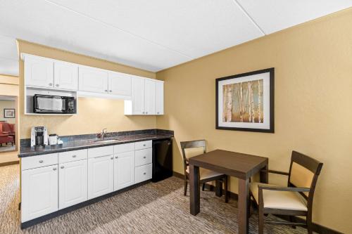 a kitchen with white cabinets and a table with chairs at Best Western Plus Mariposa Inn & Conference Centre in Orillia