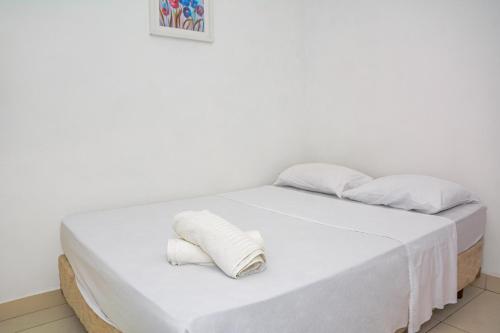 a white bed with white sheets and pillows on it at Pousada Flat Castor in Natal