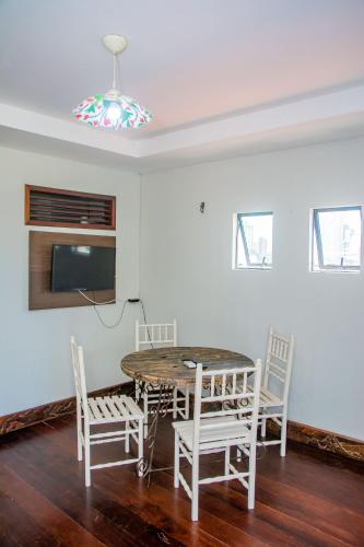 a dining room with a table and chairs and a tv at Pousada Flat Castor in Natal