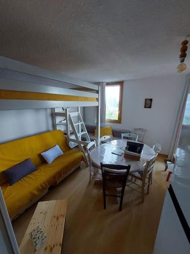 un salon avec une table et un canapé jaune dans l'établissement appartement aux coches 6 personnes 1 chambre 23m2 8 couchages, à Les Coches