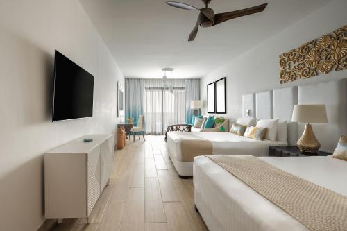 a hotel room with two beds and a flat screen tv at Sanctuary Cap Cana, a Luxury Collection Resort, Dominican Republic, Adult All-Inclusive in Punta Cana