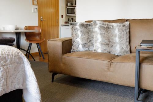a brown couch sitting in a living room with a table at Settlers Boutique Motel in Hanmer Springs