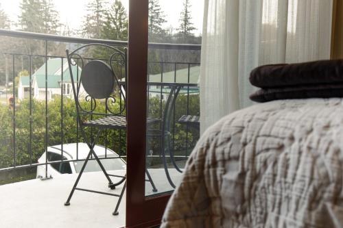 a bedroom with a bed and a chair on a balcony at Settlers Boutique Motel in Hanmer Springs