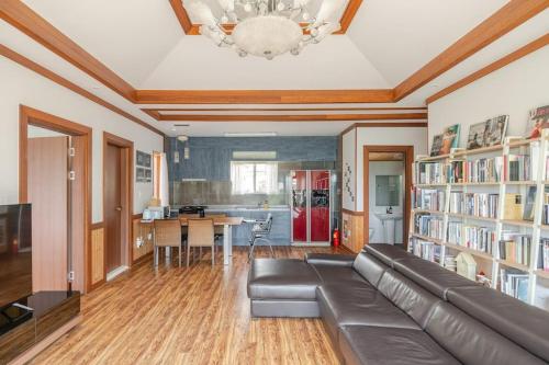 a living room with a leather couch and a kitchen at gyulpang stay in Seogwipo