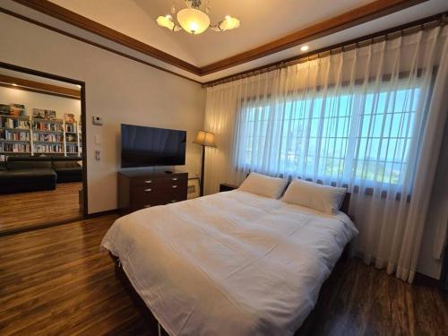 a bedroom with a large bed and a large window at gyulpang stay in Seogwipo