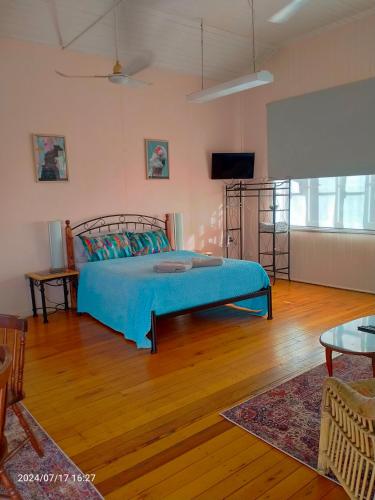 a bedroom with a bed with a blue comforter at Tamarind Gardens Camping, Caravans, Accommodation in Almaden