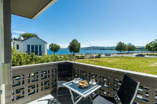 a table and chairs on a balcony with a view of the water at Stay in Town in Taupo