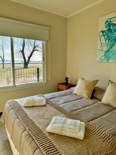 a bedroom with a large bed with two towels on it at Casa Laguna de Gomez, con increíble vista a la laguna- in Junín