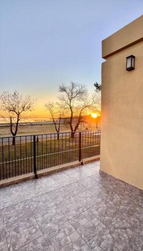 a building with a fence and a sunset in the background at Casa Laguna de Gomez, con increíble vista a la laguna- in Junín