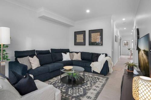 a living room with a blue couch and a table at Andrica House - Your Southern Highlands Retreat! in Mittagong