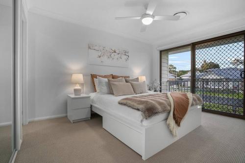 une chambre blanche avec un lit et une fenêtre dans l'établissement Andrica House - Your Southern Highlands Retreat!, à Mittagong