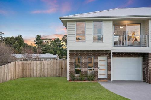 a house with a white garage door and a fence at Andrica House - Your Southern Highlands Retreat! in Mittagong