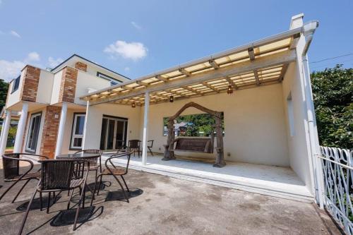 a patio with chairs and a pergola on a house at オーシャンビューテラス伊豆 in Futo