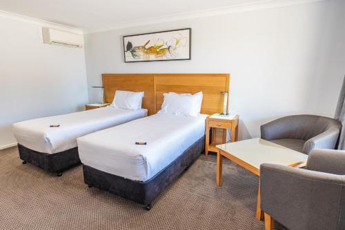 QuirindiBest Western Club Quirindi Motel的有两张床和一把椅子的酒店房间