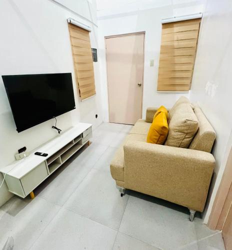 a living room with a couch and a flat screen tv at Tinyhaven Transient Cabuyao in Cabuyao