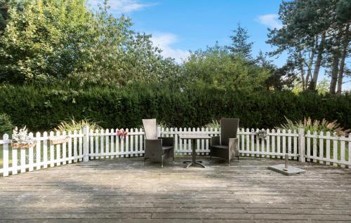 two chairs sitting in front of a white fence at 3 Bedroom Cozy Home In Nykøbing Sj in Lumsås