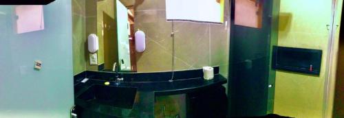 a bathroom with a mirror and a sink with phones at Apto 112 CENTRO in Araguaína