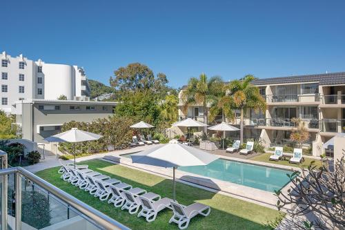 an image of a swimming pool with chairs and umbrellas at Apartments on Hastings in Noosa Heads