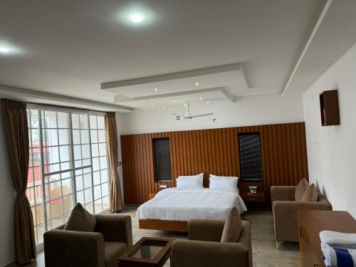 a hotel room with a bed and a couch and chairs at The Caligo resort coorg in Madikeri