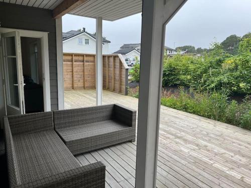 a screened in porch with a couch on a deck at Selveier leilighet, Parkering med El-bil ladder in Florø