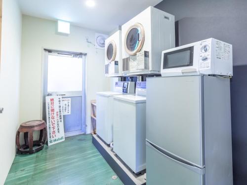 a kitchen with a refrigerator and a microwave at 旅館御宿Tabist Ritsurinsanso in Takamatsu