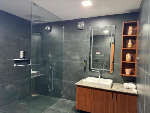 un bagno con doccia, lavandino e specchio di The Caligo resort coorg a Madikeri