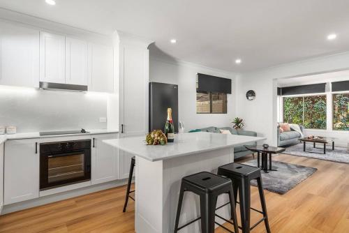 a white kitchen with a counter and stools at JezOmi Hideaway - Private, spacious, close to town in Bowral