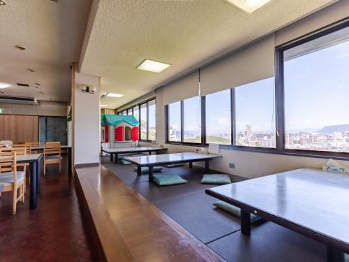 a dining room with tables and chairs and large windows at 旅館御宿Tabist Ritsurinsanso in Takamatsu