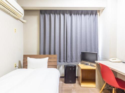 a bedroom with a bed and a desk and a television at 旅館御宿Tabist Ritsurinsanso in Takamatsu