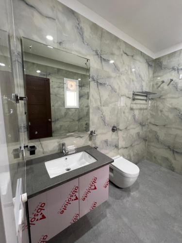 a bathroom with a sink and a toilet and a mirror at Vaidehi Resorts in Ayodhya