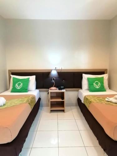 a hotel room with two beds with green pillows at Airport Poddotel Inc. in Manila