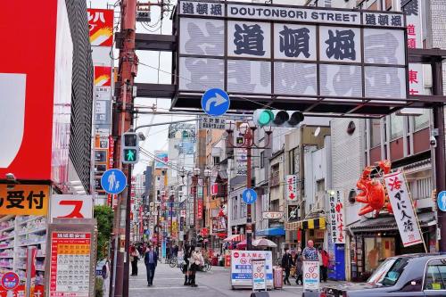 a busy city street with signs and people walking down the street at Yuzuki Dome Osaka Kujo in Osaka